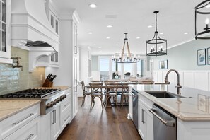 Una cocina moderna con armarios blancos, una isla central y una zona de comedor con sillas de madera.