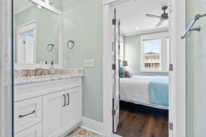 A bathroom with a white vanity, a large mirror, and a shower area.