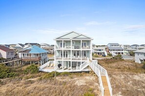 Una casa frente al mar de varios pisos, con un muelle de madera y una escalera que conduce a la parte superior.