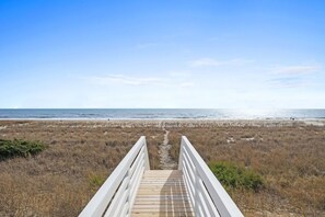 Pasarela de madera que conduce a una playa con cielo despejado.