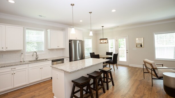 A modern kitchen with white cabinets, a granite countertop, a stainless steel refrigerator, and a bar area with stools. - Great Location! 4 Bed / 4.5 Bath House in Pinehurst! (Pinehurst)