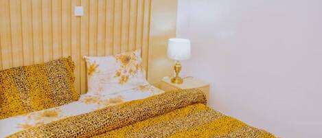 A bed with a leopard print bedspread, a bedside lamp, and a pillow with a floral pattern.