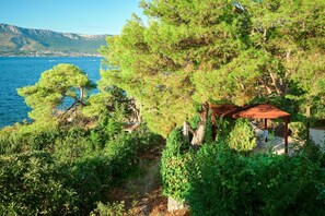 Zona costera con un mirador, abundante vegetación y vistas al mar y montañas distantes.