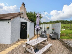 A rustic cottage with a heart-shaped door, a wooden bench, and outdoor seating. - High Wreah Bolt Hole (Whitehaven)
