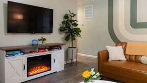 Ein Wohnzimmer mit Kamin, einem an der Wand befestigten Fernseher, einer Couch und einem Couchtisch mit Dekoration.