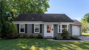 Ein eingeschossiges Haus mit Veranda, Garage und gepflegtem Rasen.