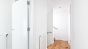 Un couloir aux murs blancs, avec un radiateur et un plancher en bois.