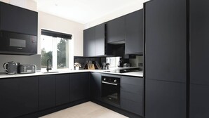 Una cocina moderna con armarios oscuros, microondas integrado, tostadora y una ventana que proporciona luz natural.