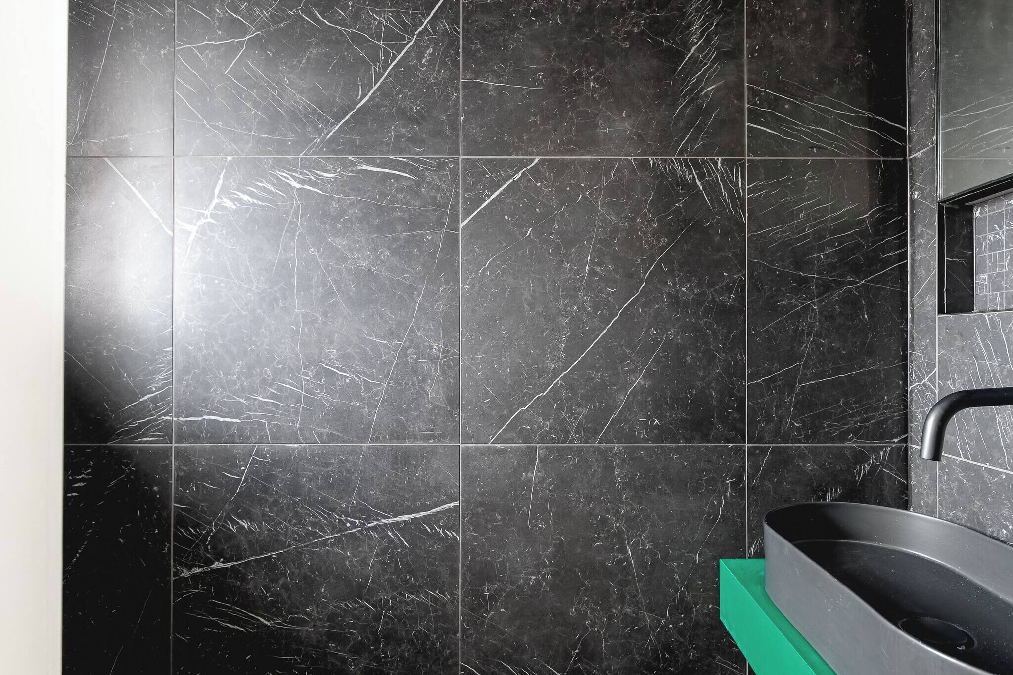 A bathroom with black marble tiles and a modern sink.
