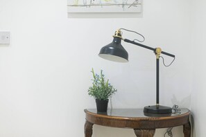 A desk lamp on a wooden table with a potted plant beside it.