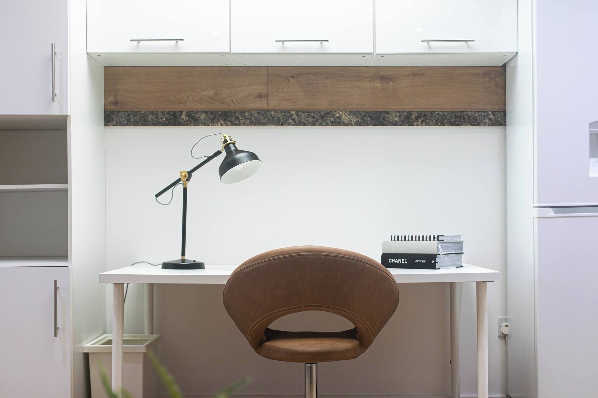 Un espace de travail comprenant un bureau, une chaise, une lampe et des livres.