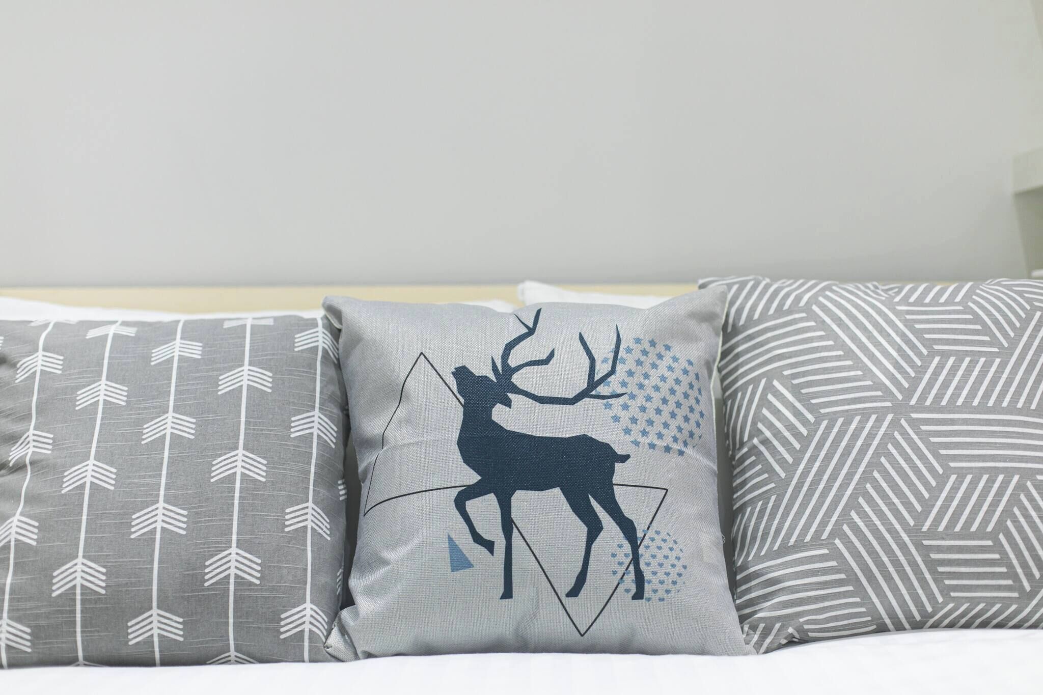 Three pillows with different patterns on a bed.