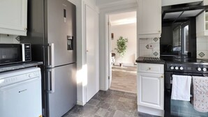 Une cuisine moderne dotée d’appareils électroménagers en acier inoxydable, de meubles blancs et offrant une vue sur la salle à manger.