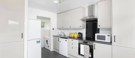 A modern kitchen with white cabinetry, a built-in oven, microwave, and a dishwasher.
