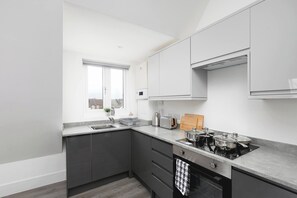 A modern kitchen with dark cabinets, a gas stove, a sink, and a window.