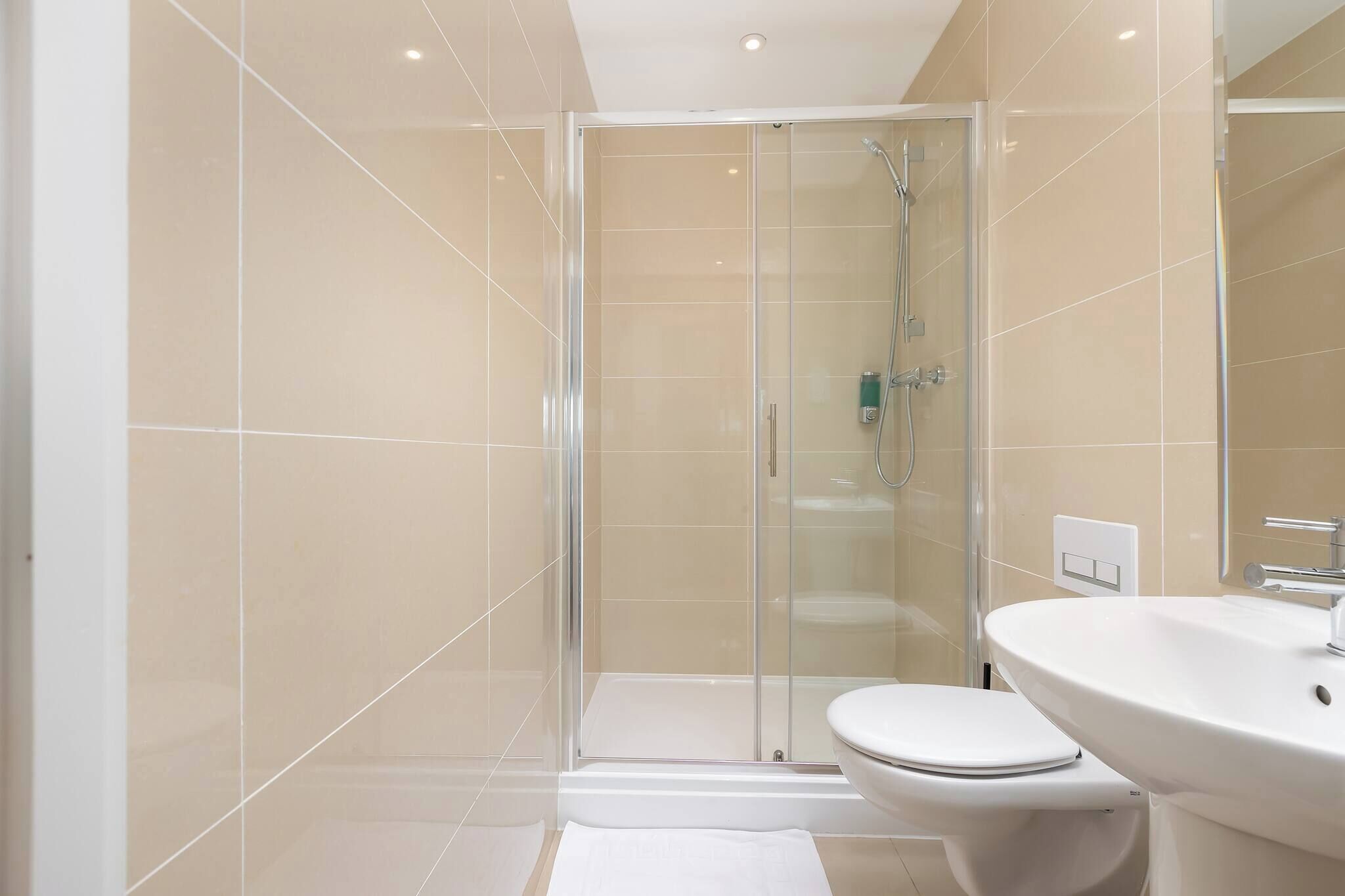 Un bagno moderno con doccia in vetro, un water bianco e un lavandino spazioso.