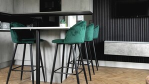 A modern kitchen with bar stools, a microwave, and a flat-screen TV. - Skyvillion -1bed Cockfosters Near Alexandra Palace (Barnet)