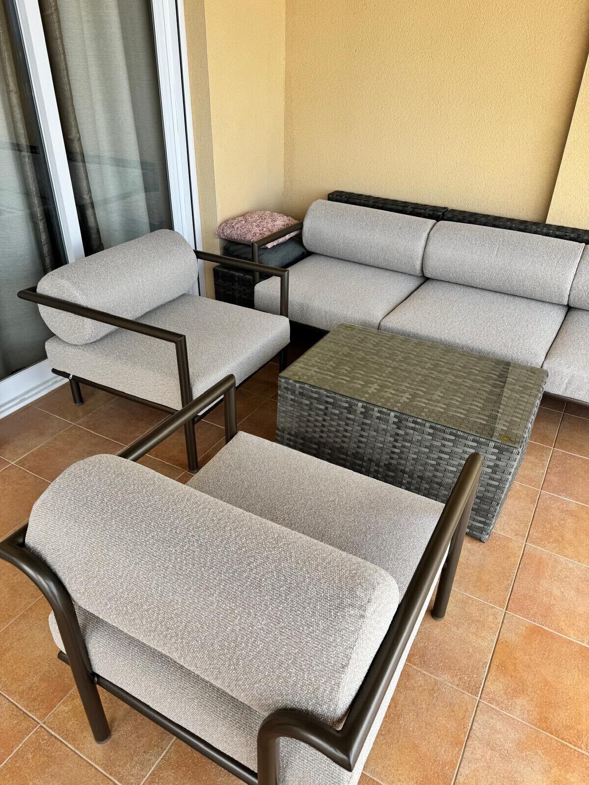 A patio area with a sofa, two chairs, and a small table.