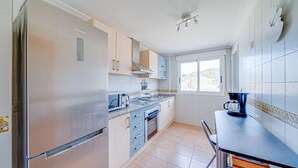 A modern kitchen with a refrigerator, stove, sink, and window. - AL Piso en El Poblet 3 dormitorios (El Campello)