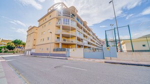 A multi-story residential building with balconies, a gated entrance, and a clear sky. - AL Piso en El Poblet 3 dormitorios (El Campello)