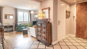 Een ruime woonkamer met een houten plafond, een eettafel met stoelen, een bank en een televisie.