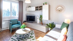 Een moderne woonkamer met een televisie, bank en een eetgedeelte met tafel en stoelen.