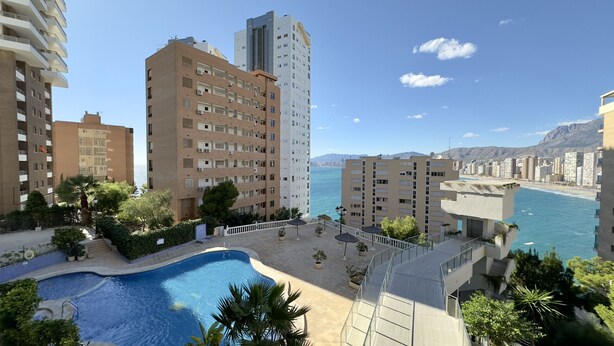 Ein Wohngebäude mit Pool, Balkonen und Meerblick.