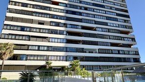Un immeuble de grande hauteur doté de nombreux balcons et d’une façade en verre.
