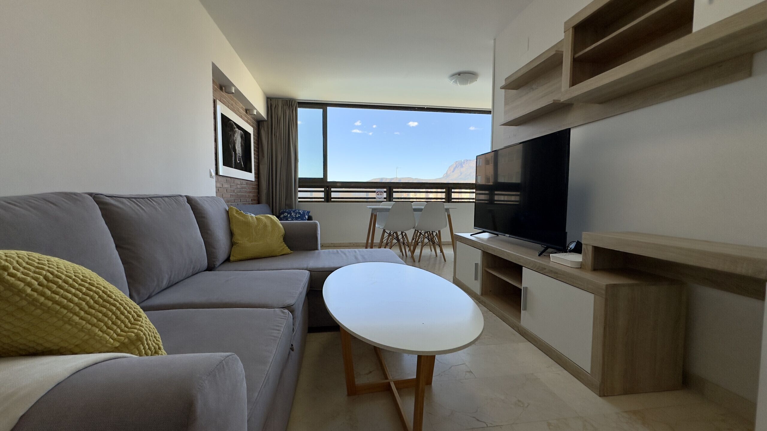 A modern living room with a gray sofa, a white coffee table, and a flat-screen TV.
