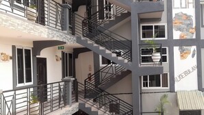 Un edificio de varios pisos con una escalera central, balcones y una variedad de estilos de ventanas.