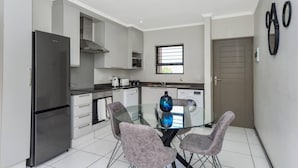 Una cocina moderna con refrigerador, estufa y mesa de comedor con sillas.