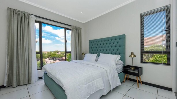 Un dormitorio con una cama grande, vistas al exterior y una ventana con persianas.