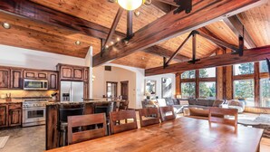 A spacious kitchen with wooden beams, a large dining table, and modern appliances. - PONY47 - Stunning River Front Home, Community Pool (Sunriver)