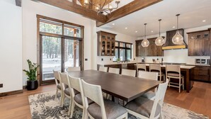 A spacious kitchen with a large dining table, wooden cabinets, and pendant lighting. - SUNS93 - Gorgeous Caldera Springs Home (Sunriver)