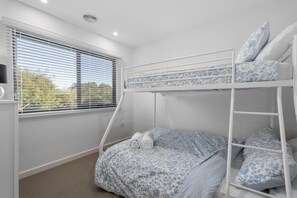 Ein Schlafraum mit Etagenbett, Fenster, Heizkörper und Teppichboden.