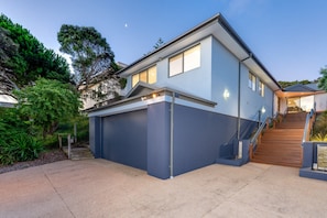 A modern two-story house with a garage, a staircase, and a well-maintained garden. - Captains Quarters (Rye)