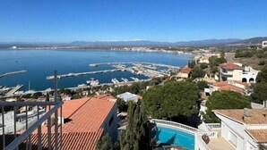 Une vue sur la côte, avec un port de plaisance, des bâtiments et un ciel bleu dégagé.