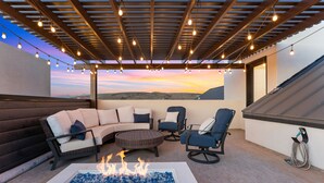 An outdoor patio with a fire pit, seating, and string lights. - Vinnie's Beach House: Private Pool, Lagoon + Beaches (St George)