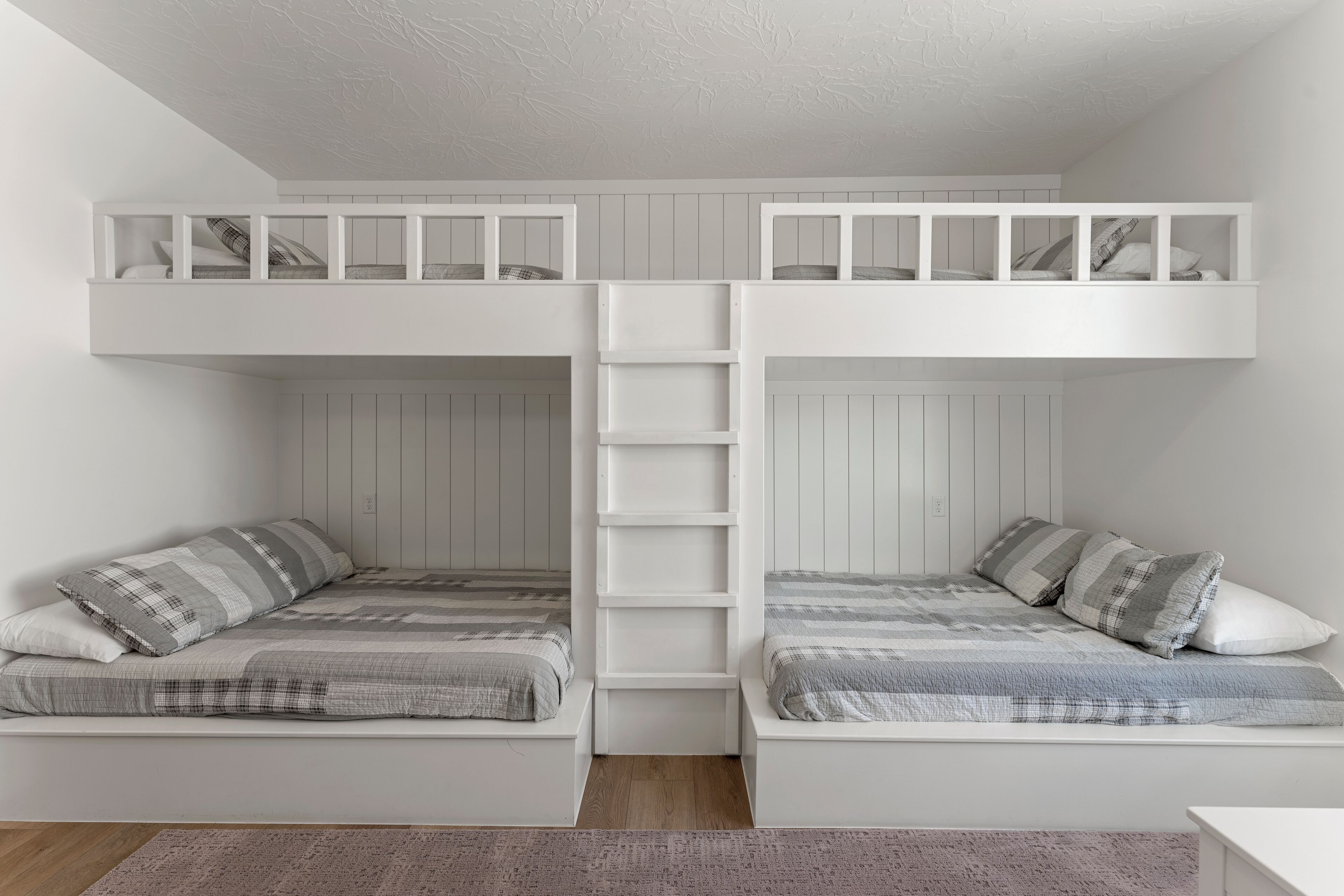 A bunk bed room with white walls and a wooden floor.