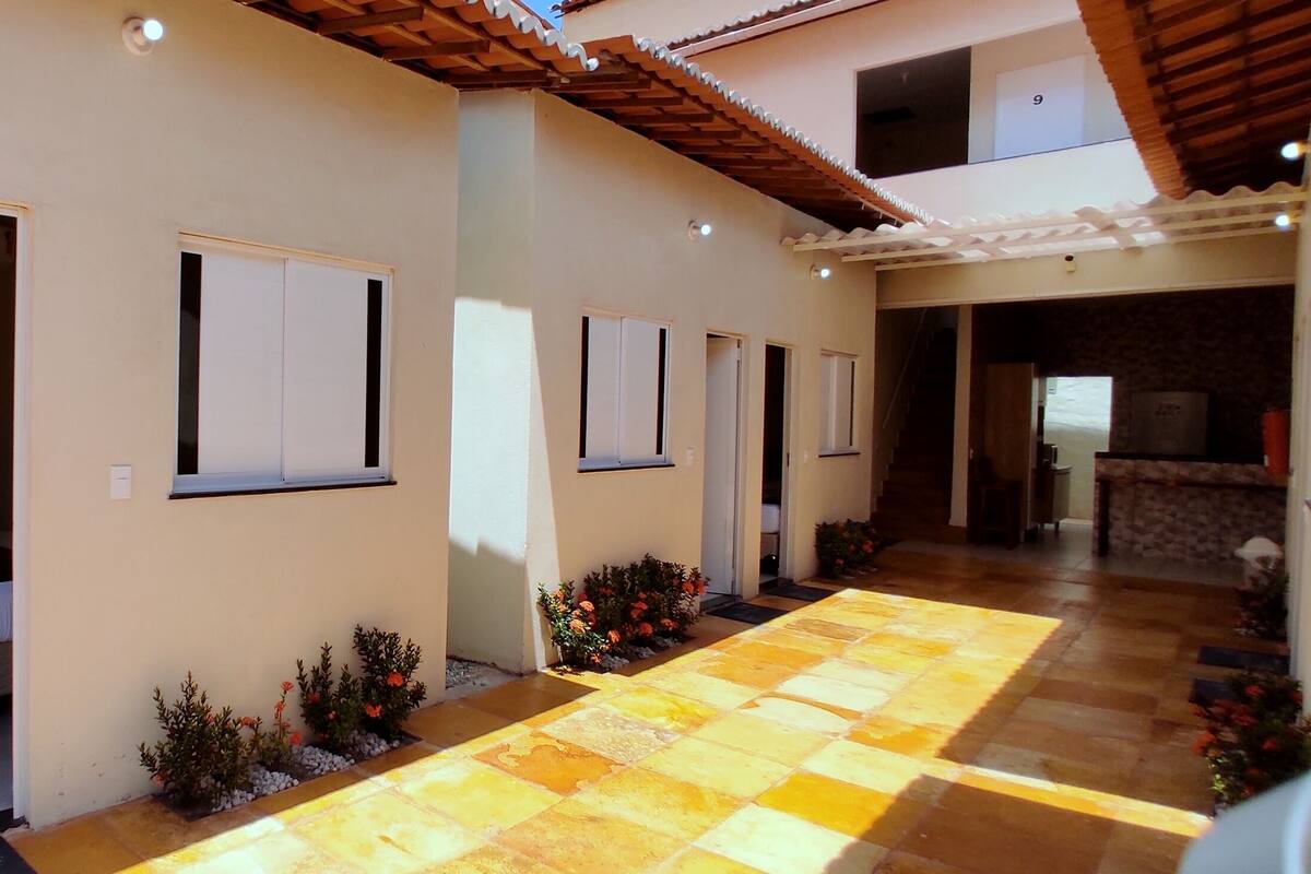 Pasillo de hotel con varias habitaciones, suelo de baldosas y pequeñas plantas a lo largo del pasillo.