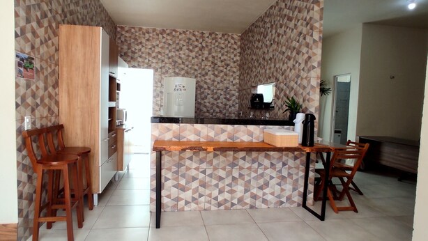 Una cocina con un salpicadero de diseño geométrico, armarios de madera, un refrigerador, una cafetera y una barra con taburetes.