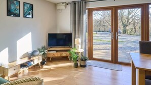 En moderne stue med et fladskærms-tv, møbler i træ og en skydedør til en baghave.