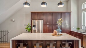 A modern kitchen with a large island, dark wood cabinets, stainless steel appliances, and pendant lighting. - Luxury Downtown Getaway With Breathtaking Views (Houston)