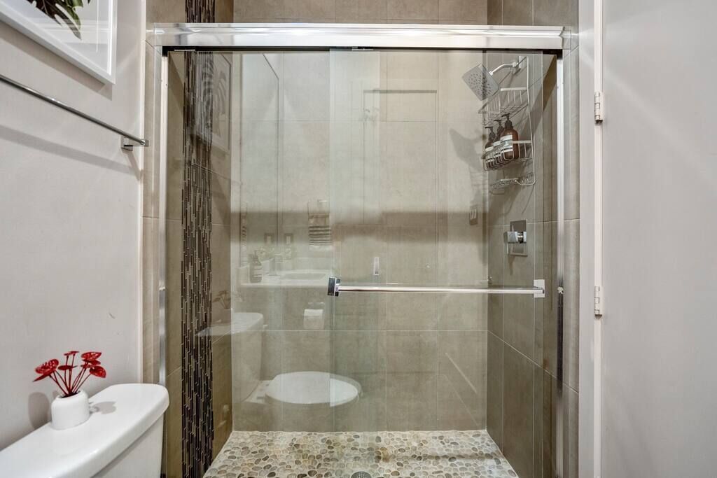 A glass-enclosed shower stall with a toilet and sink visible through the glass.