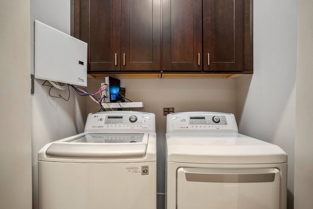 A laundry area with two front-loading washing machines and a wall-mounted dryer.