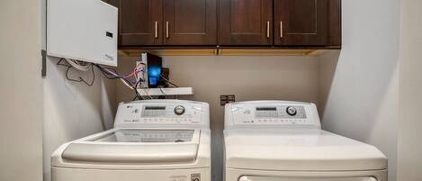 A laundry area with two front-loading washing machines and a wall-mounted dryer.