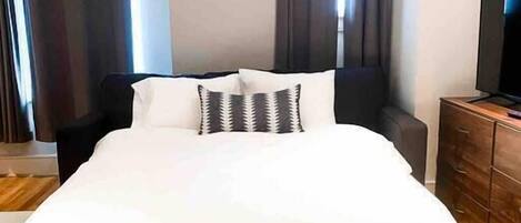 Una camera d'albergo con un letto grande, una TV a schermo piatto e un pavimento in legno.