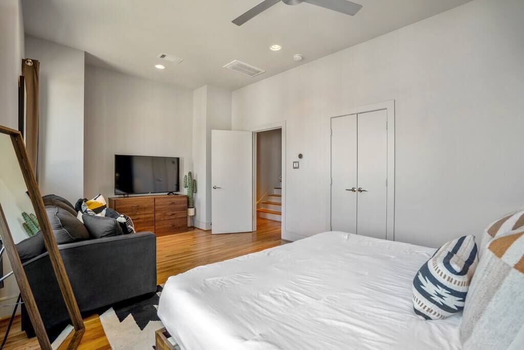 Een moderne slaapkamer met een groot bed, een sofa, een televisie en een trap.