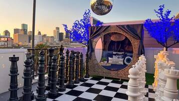 A rooftop with a chessboard, a disco ball, and a view of the city skyline.