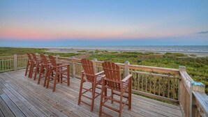 Eine Holzterrasse mit Stühlen mit Blick auf Strand und Küstenlandschaft.